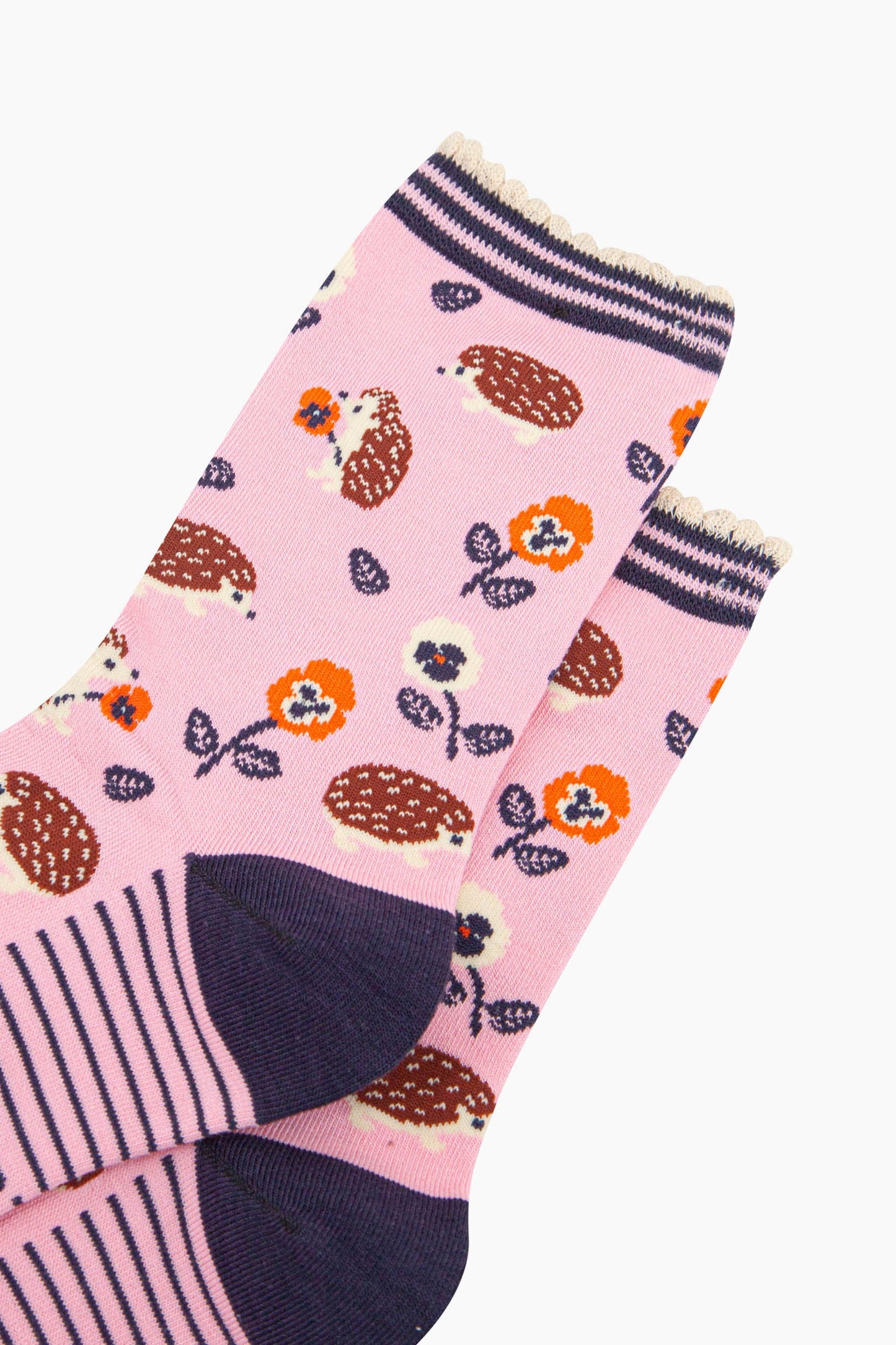 close up of the pattern. the hedgehogs are brown and beige, some are sitting holding orange pansy flowers, others are walking among the flowers.