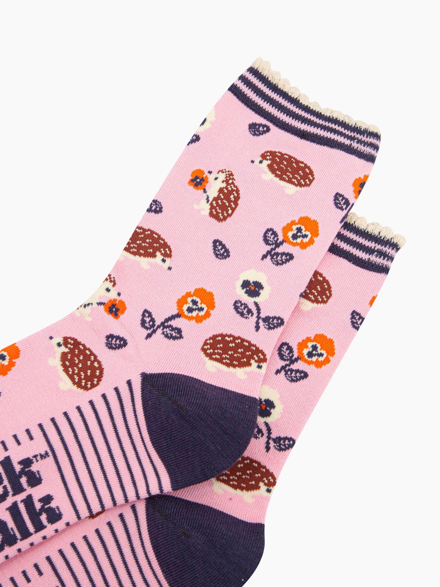 close up of the pattern. the hedgehogs are brown and beige, some are sitting holding orange pansy flowers, others are walking among the flowers.