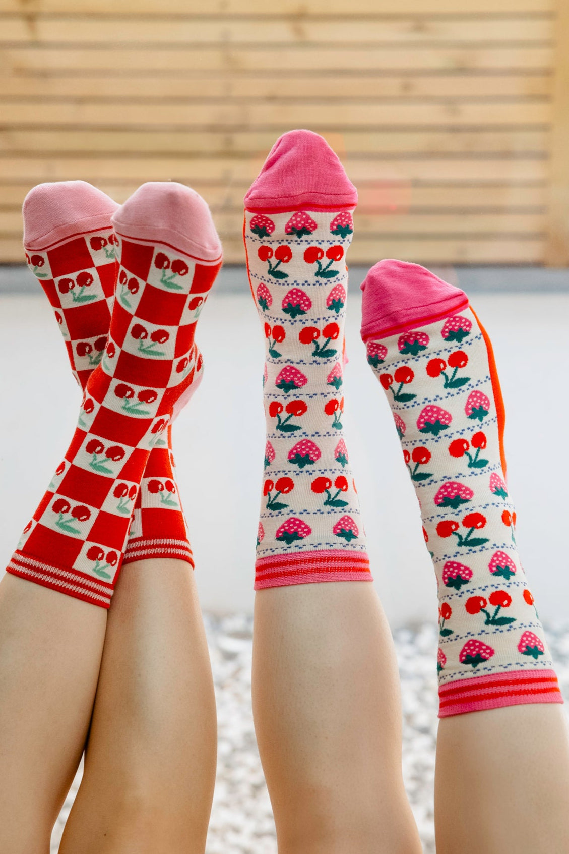 womens-bamboo-socks-cream-red-cherry-squares-and-womens-bamboo-socks-cream-strawberry-cherry-fair-isle-two-woemn-posed-feet-to-sky