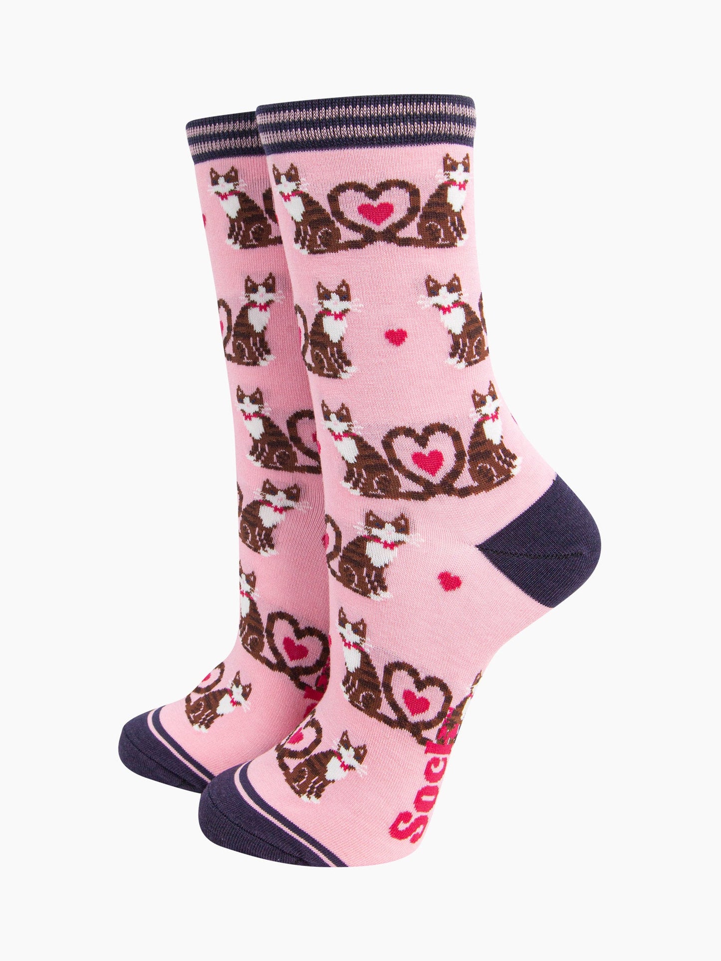 the pair of pink cat and love heart socks laying flat, one overlapping the other. showing clearly the light pink background of the socks which is contrasted by the all over pattern of cats and hearts. the sock talk logo is visible on the base of the sole.