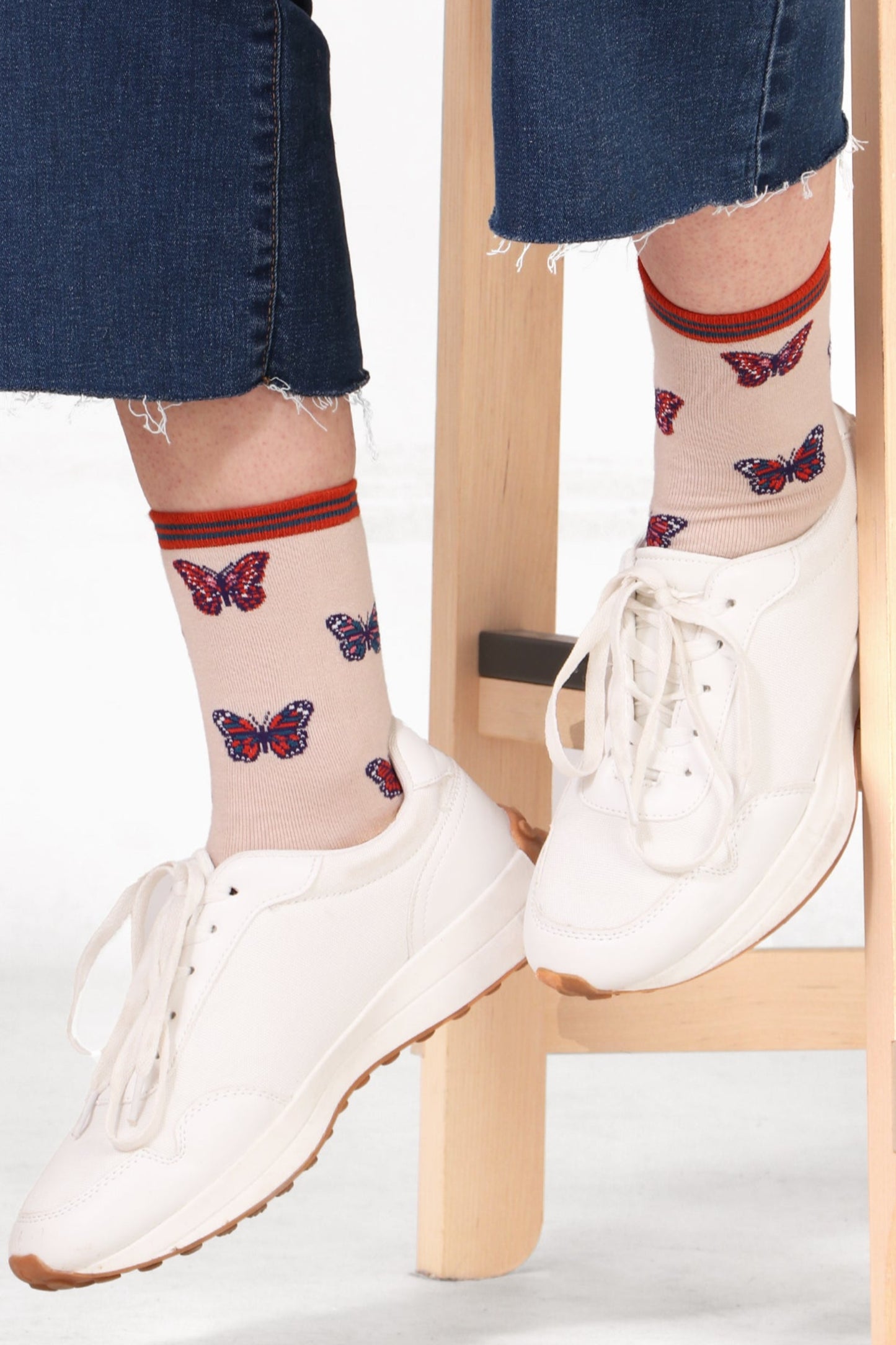 Model sitting on table wearing women's butterfly print bamboo socks