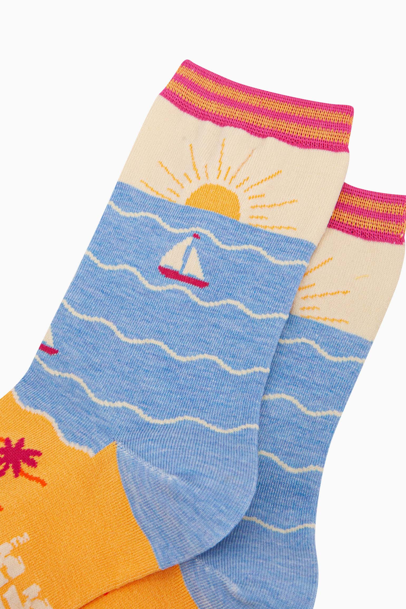 womens-bamboo-socks-cream-blue-beach-sunset-close-up-setting-sun-on-the-ankle-yellow-sandy-beach-blue-ocean-with-sail-boat-depicted-on-the-body-of-the-design