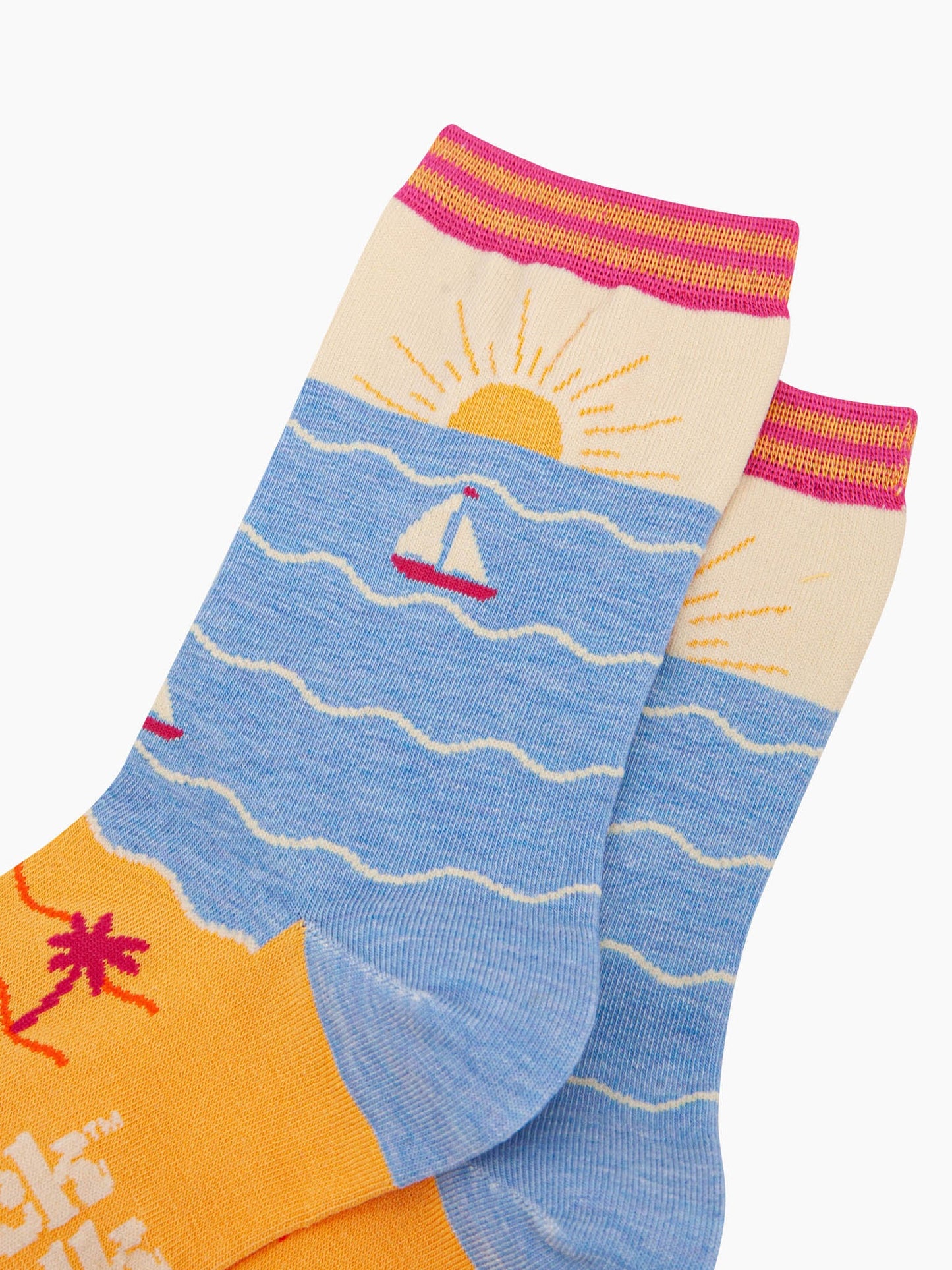 womens-bamboo-socks-cream-blue-beach-sunset-close-up-setting-sun-on-the-ankle-yellow-sandy-beach-blue-ocean-with-sail-boat-depicted-on-the-body-of-the-design