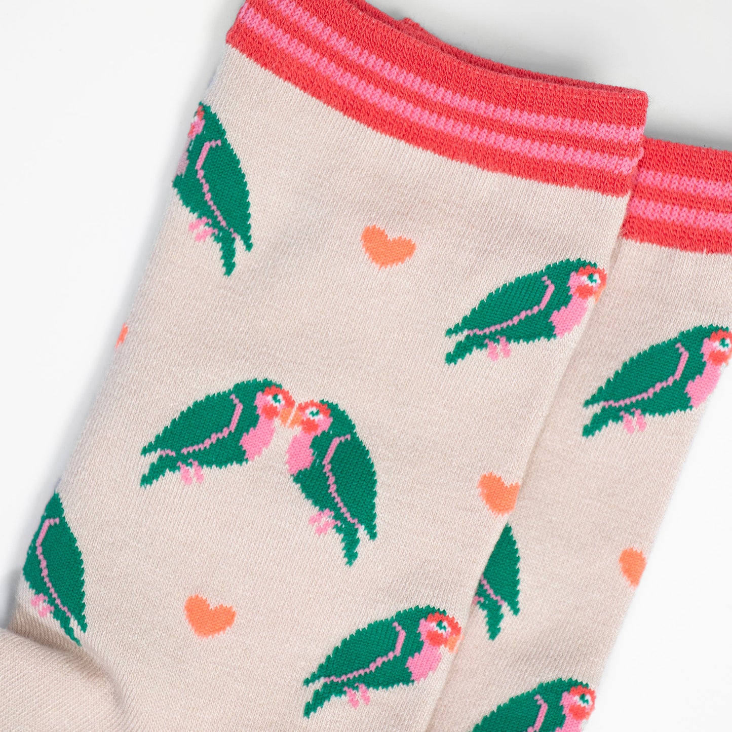 close up of the love bird and heart pattern, the love birds are green with pink bellies and beaks, they are in pairs and leaning in together like they are kissing. the love hearts are a pale peach pink colour