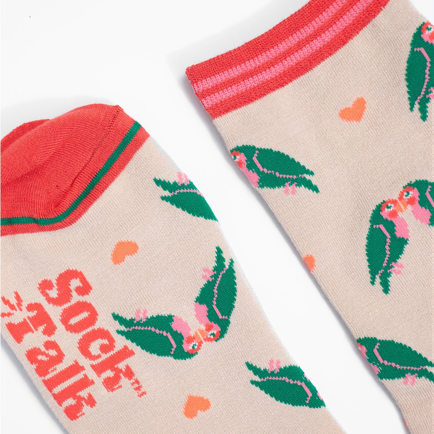 close up of the toe and cuff, the toe is a coral pink with a green border stripe, the cuff is pink and coral striped