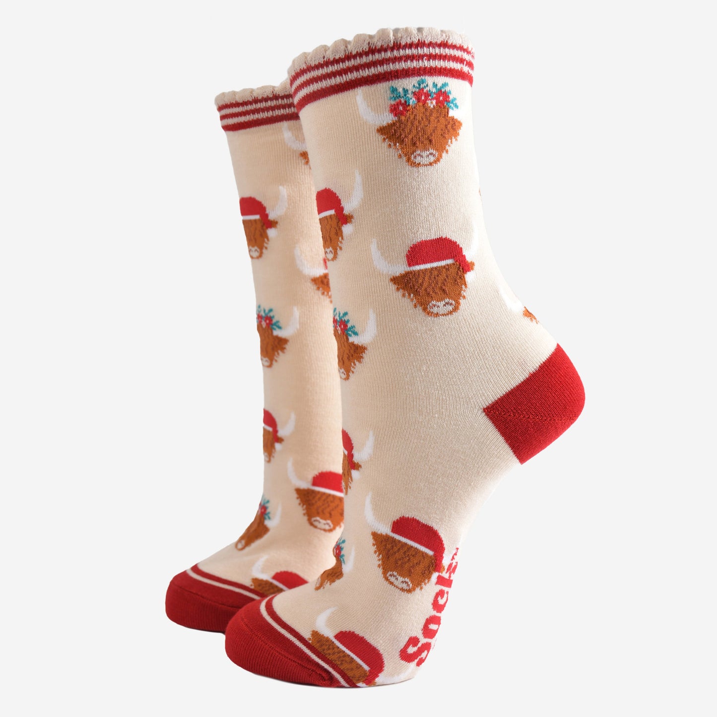 cream socks with red heel, toe and striped cuff featuring a pattern of highland cows wearing santa hats and floral crowns