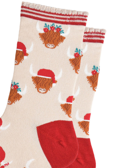 close up of the highland cow pattern on the socks, there are two designs, one with the cow wearing a red santa hat, the other the cow is wearing a festive green and red floral wreath as a crown