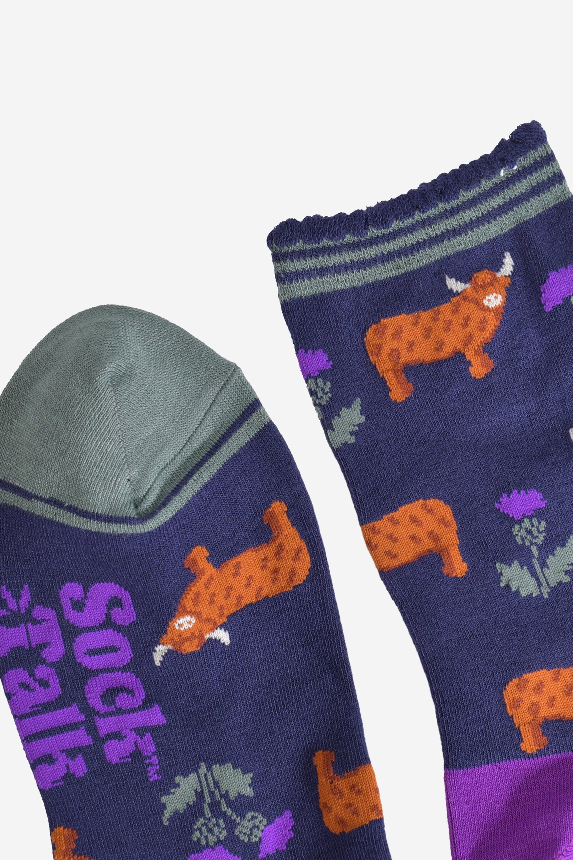 close up of the cuff and toe of the socks, the toe is green and the cuff had three green thin horizontal stripes and a scalloped edge