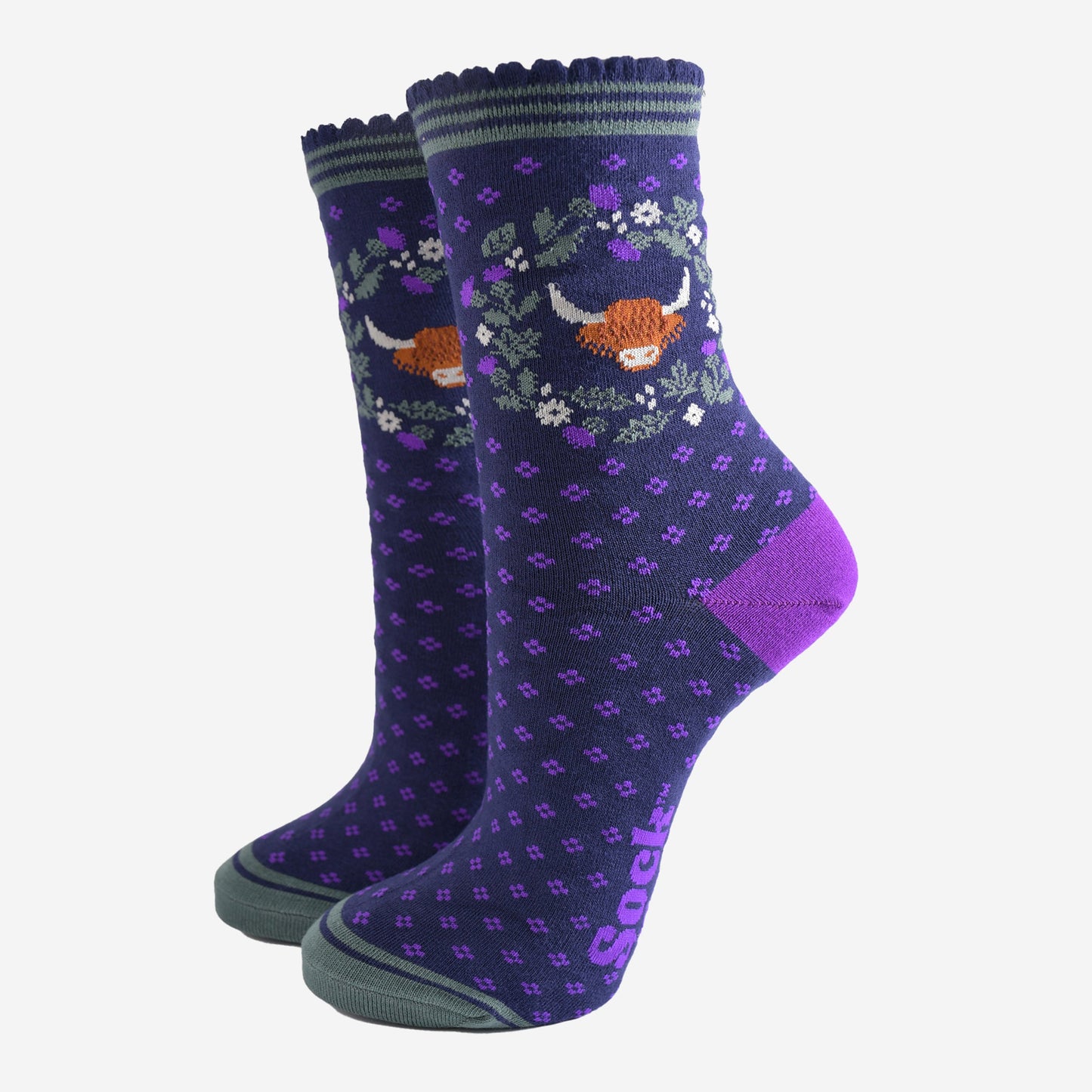 navy blue and purple ankle socks with scalloped cuffs featuring a highland cow and a wreath featuring purple and green scottish thistle flowers