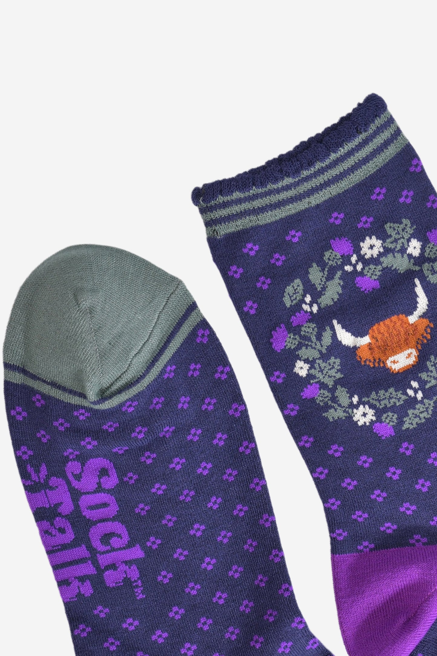 close up of the cuff and toe of the socks, the toe is green and the cuff had three green thin horizontal stripes and a scalloped edge