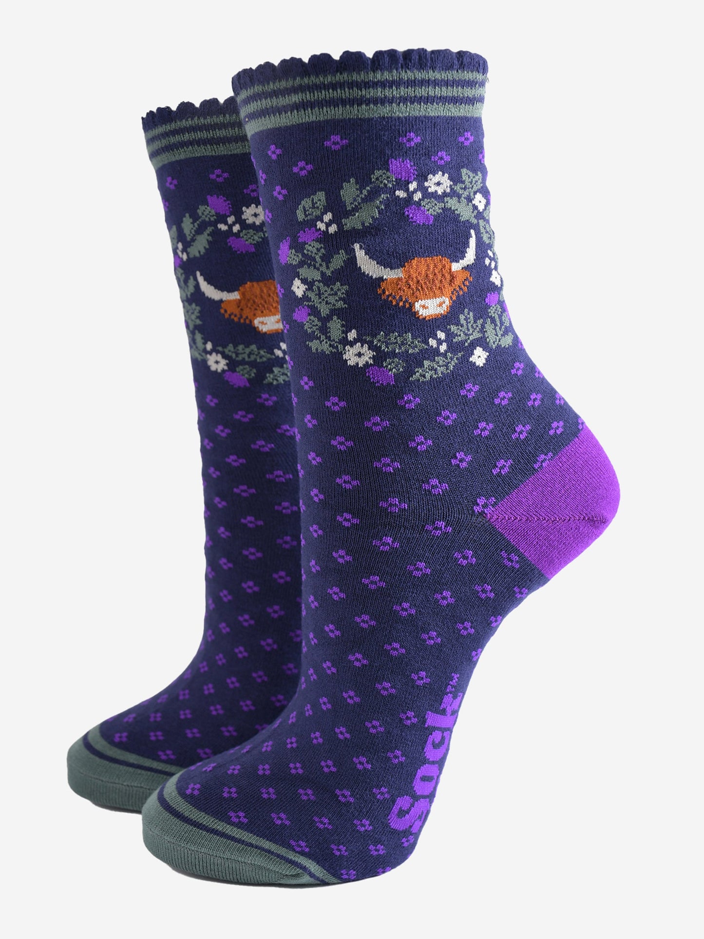 navy blue and purple ankle socks with scalloped cuffs featuring a highland cow and a wreath featuring purple and green scottish thistle flowers
