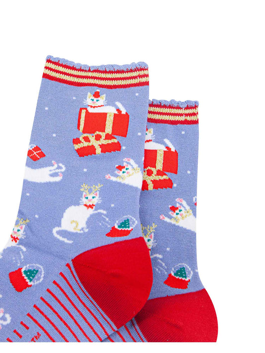 close up of the white cats on the socks, they are sitting inside gift boxes, playing with presents and pawing at snow globes
