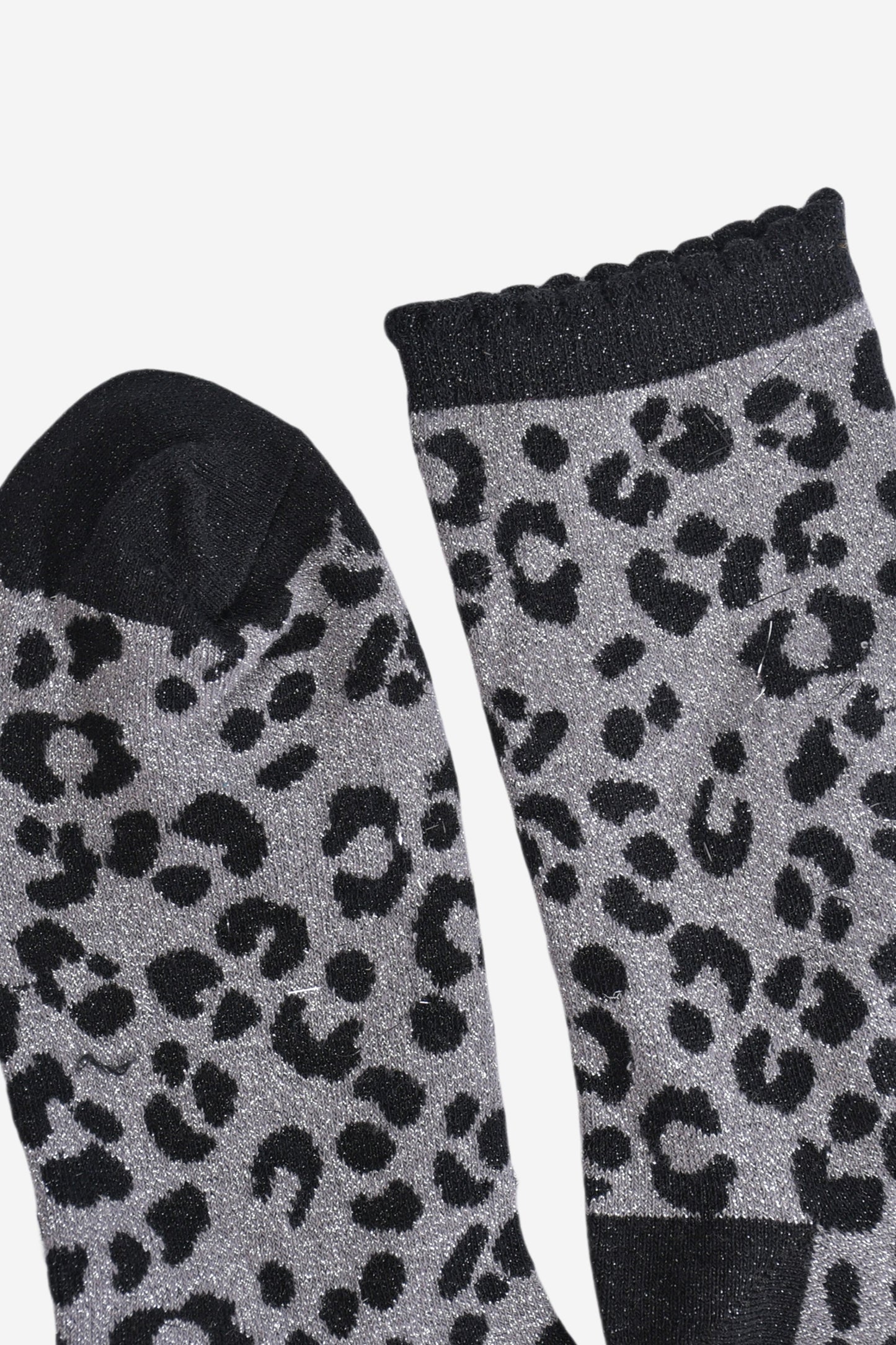 showing the toe and cuff of the socks, the toe is black and sparkly like the black leopard print pattern, the cuff is also black and sparkly and has a scalloped edge