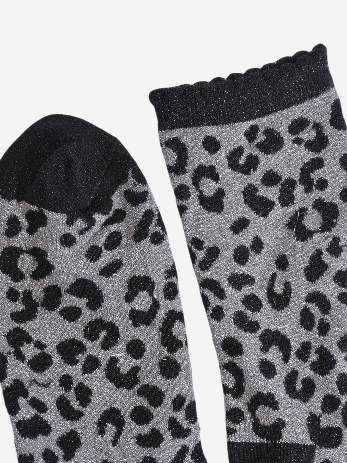 showing the toe and cuff of the socks, the toe is black and sparkly like the black leopard print pattern, the cuff is also black and sparkly and has a scalloped edge