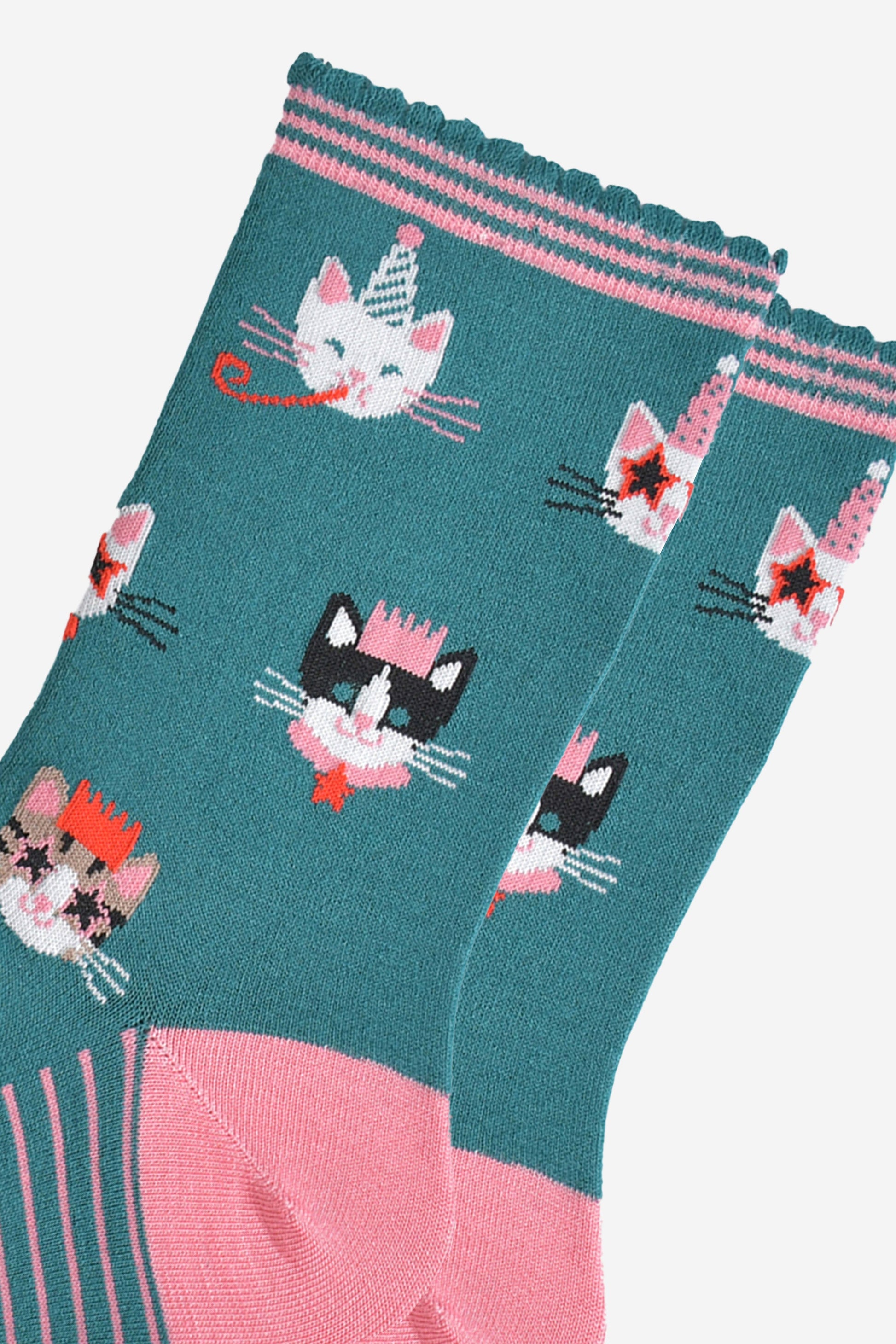 close up of the cat design on the socks, there is a white cat wearing a party hat and blowing a party trumpet, a white cat with a party hat wearing star shaped sunglasses, a black and white cat wearing a pink party crown and a tabby cat wearing a party crown and glasses.