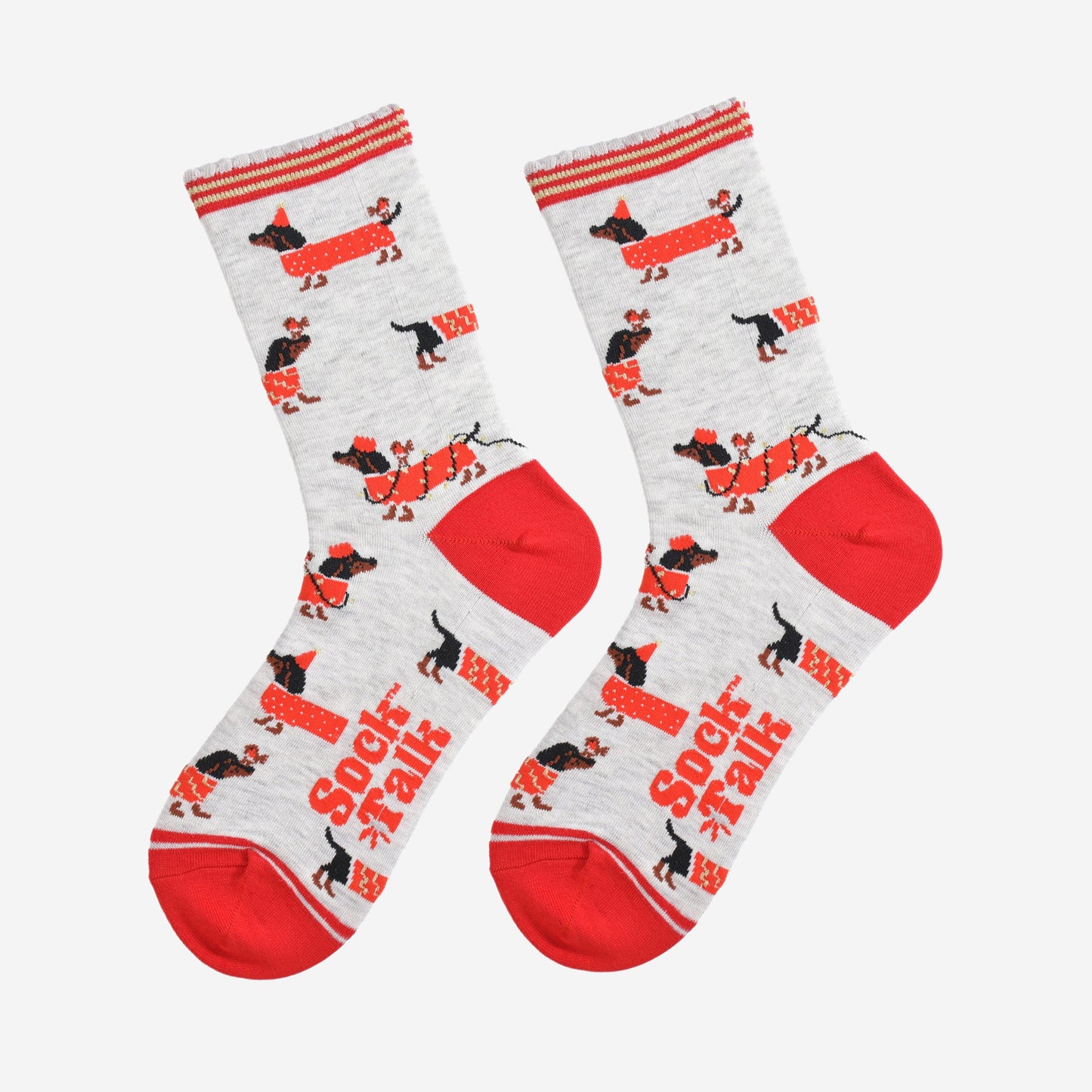 showing the socks laying flat, there is an all over pattern of black sausage dogs wearing red festive coats, party lights and hats. there are also red robins playing with the sausage dogs