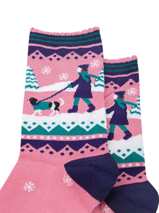 pink ankle socks with blue and green accents, showing a snowy winter scene with a woman walking a king charles spaniel