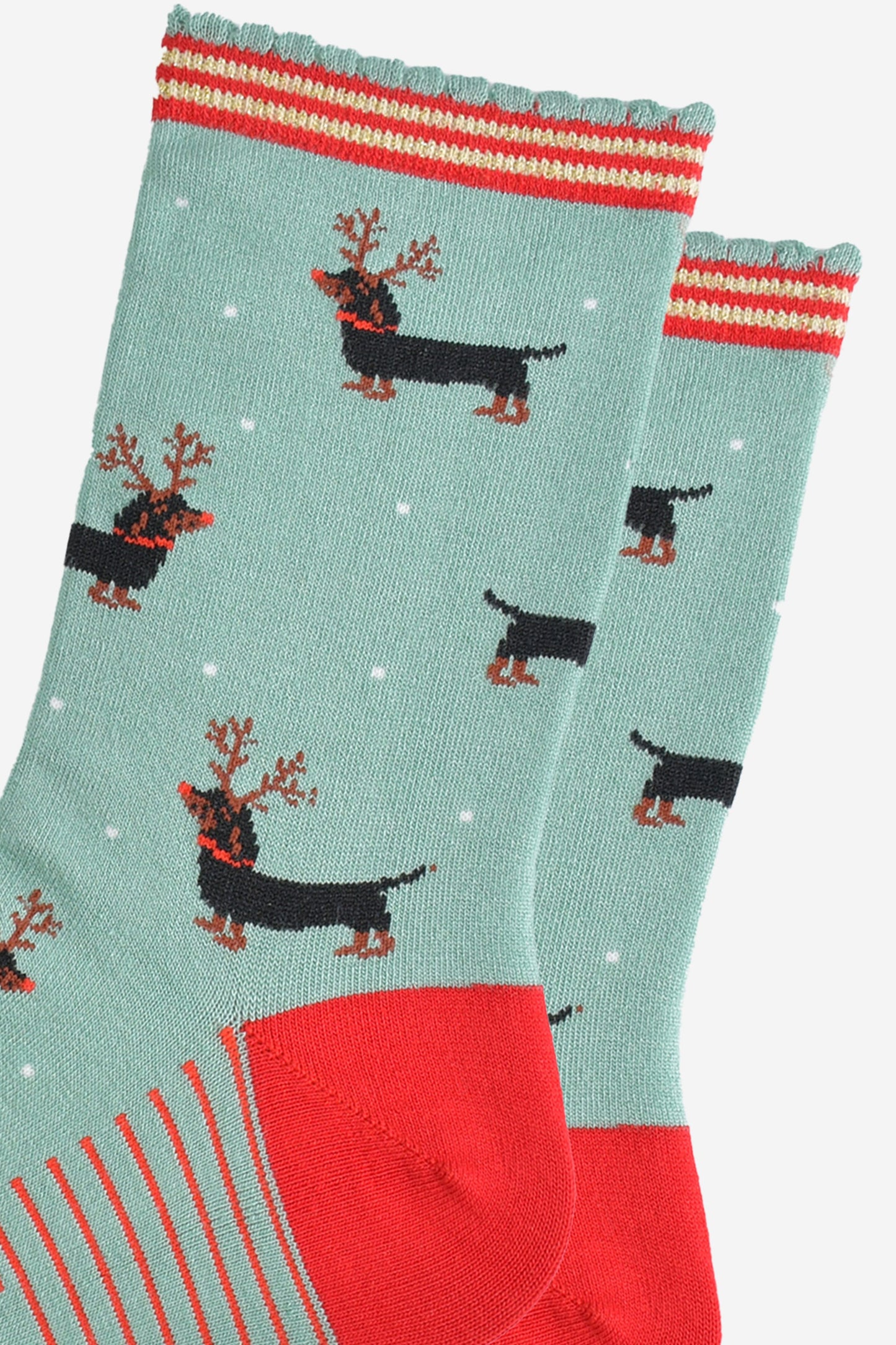 close up of the sausage dog pattern, the dogs are black and tan, traditional markings, they are wearing a set of brown reindeer antlers and wearing red noses like rudolph.