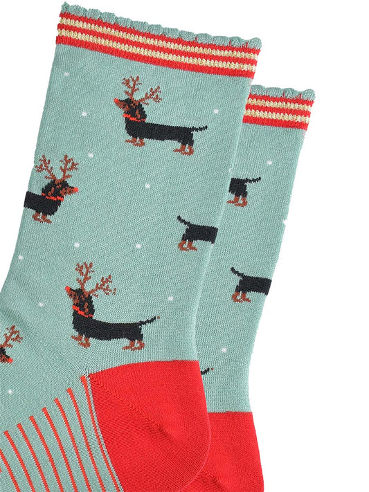 close up of the sausage dog pattern, the dogs are black and tan, traditional markings, they are wearing a set of brown reindeer antlers and wearing red noses like rudolph.