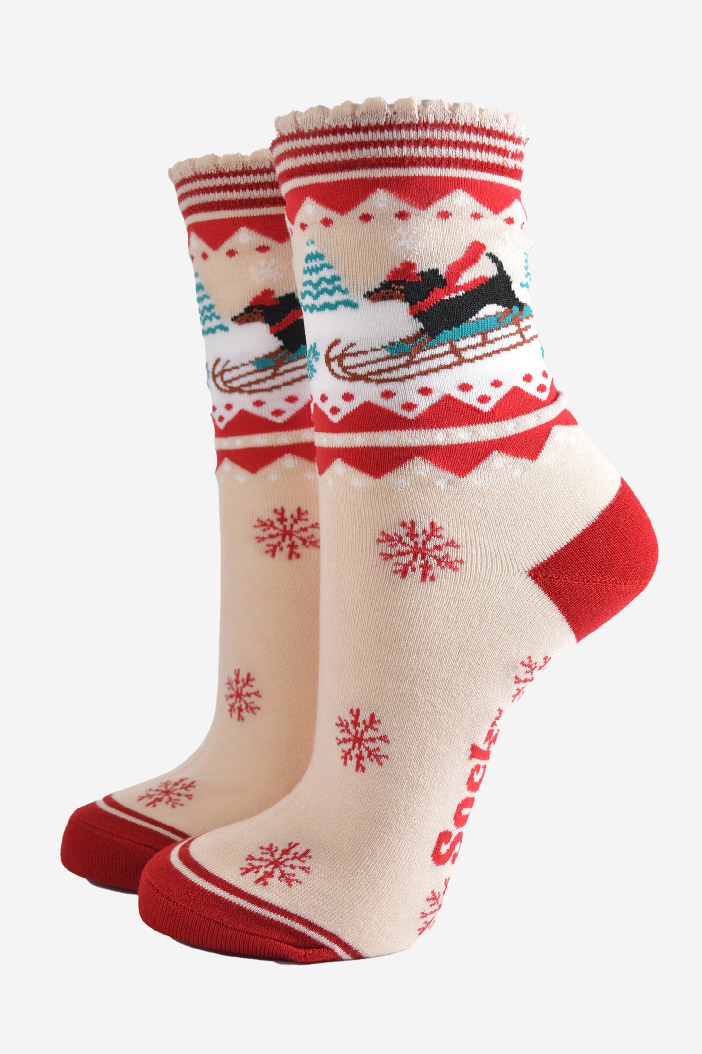 cream and red bamboo socks featuring a sledging sausage dog and red snowflake pattern
