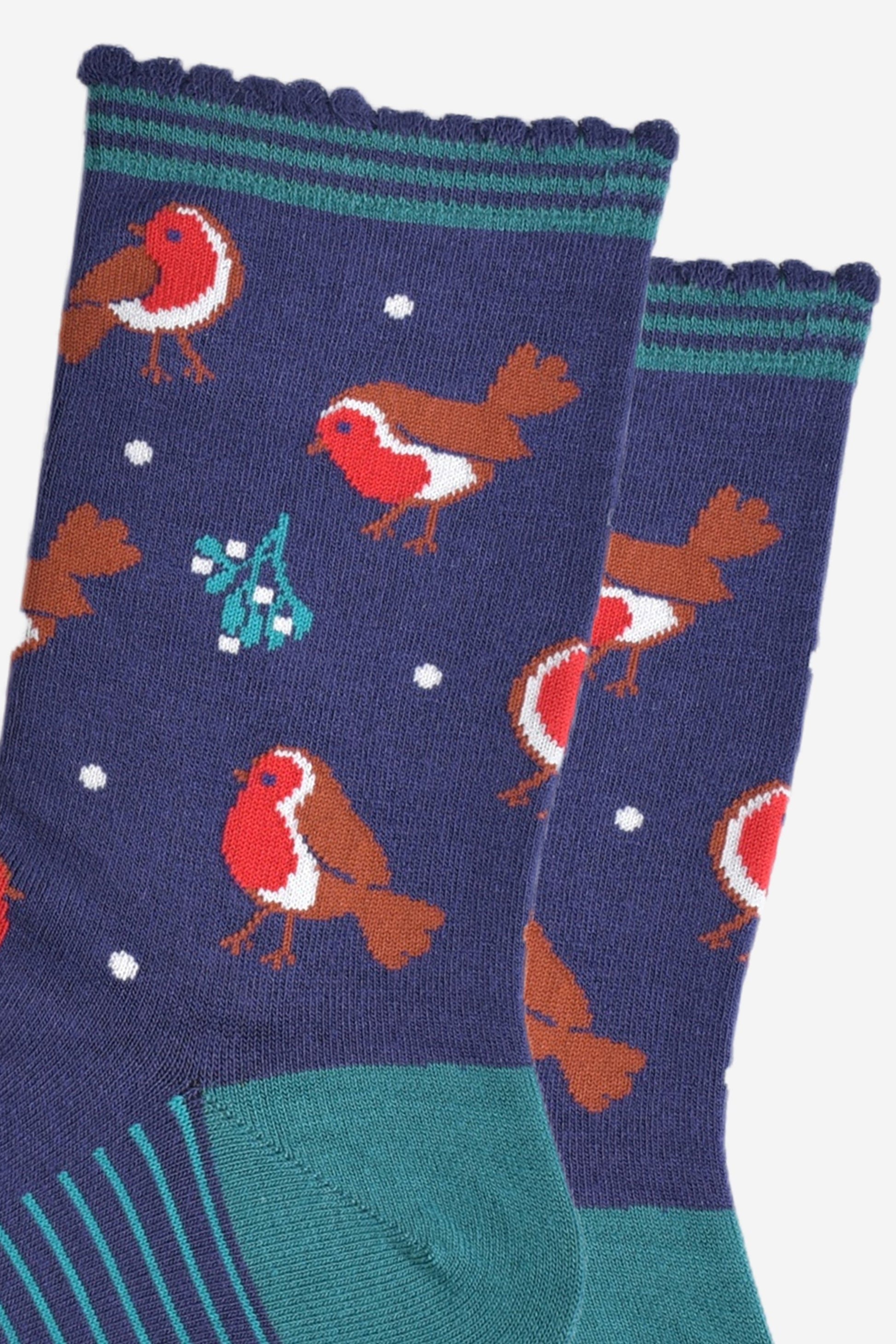 close up of the red robins and mistle toe pattern on the socks, also visible are small white dots designed to look like subtle falling snowflakes