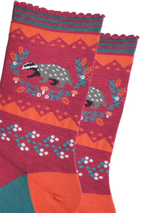 close up of the badger and wreath on the ankle of the socks, the badger is grey and black and the wreath is freen with red toadstool and autumn leaf accents