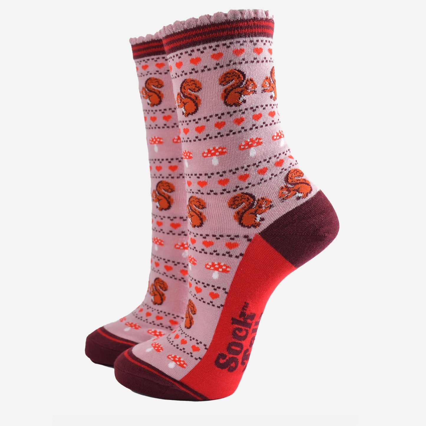 pink socks with a fair isle style pattern featuring toadstools, red love hearts and squirrels