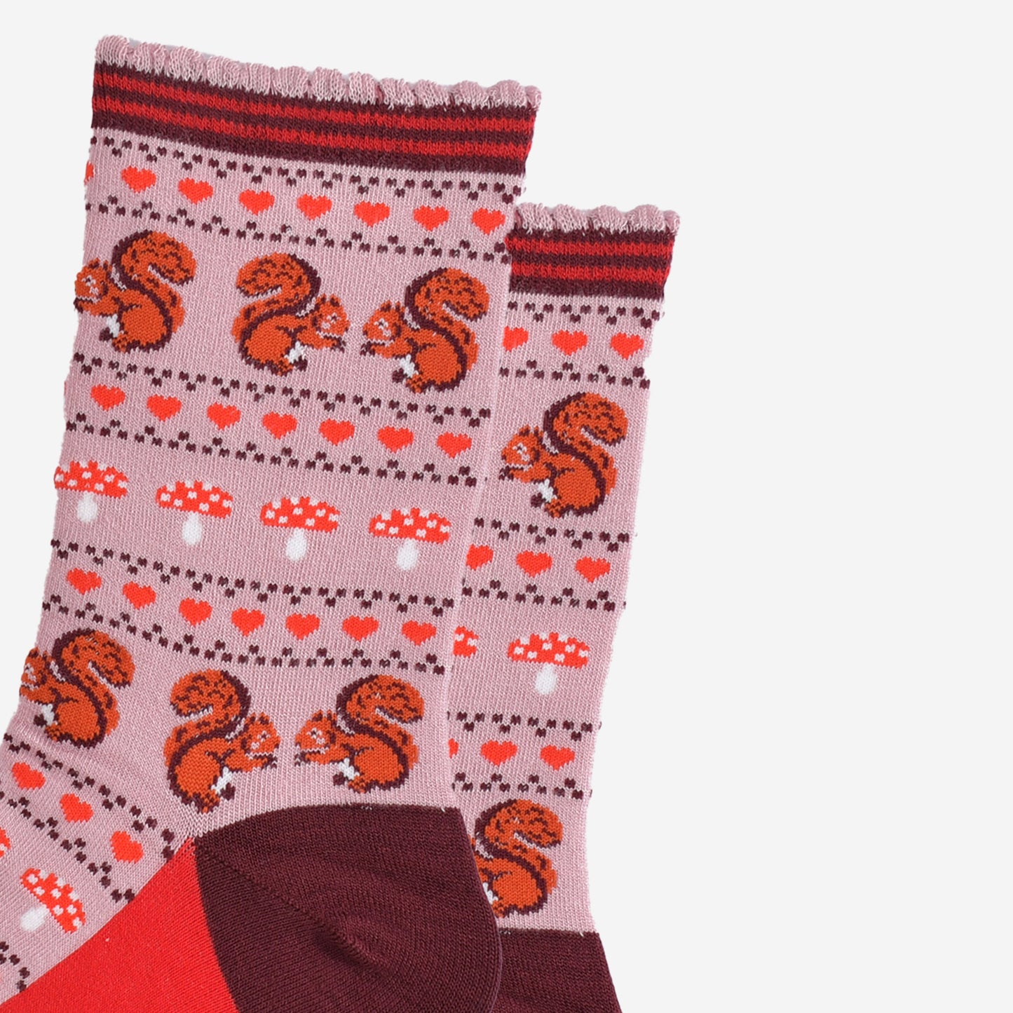 close up of the red squirrels, red love hearts and red toadstool fair isle pattern on the pink bamboo socks