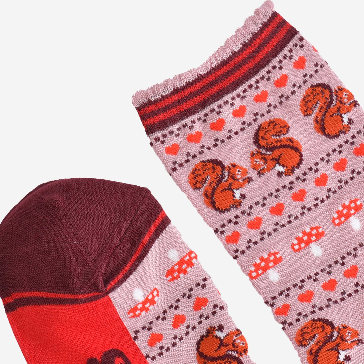 close up of the toe and cuff of the socks, the toe is burgundy with a red striped outline, the cuff is scalloped with a light pink edge and red and burgundy striped trim