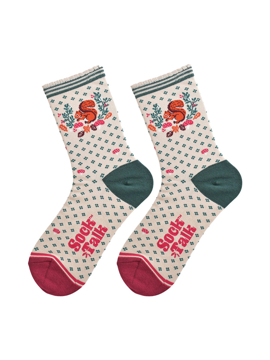 cream and green squirrel wreath socks laying flat, showing the all over green floral pattern and dominant red squirrel and wreath design on the ankle of the socks