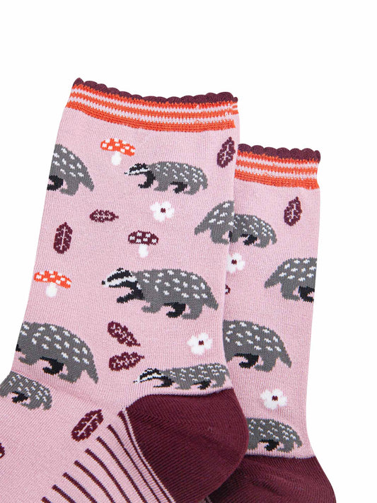 close up of the woodland badger pattern, the socks have grey and black badgers, red toadstools, burgundy red leaves and white flowers on them