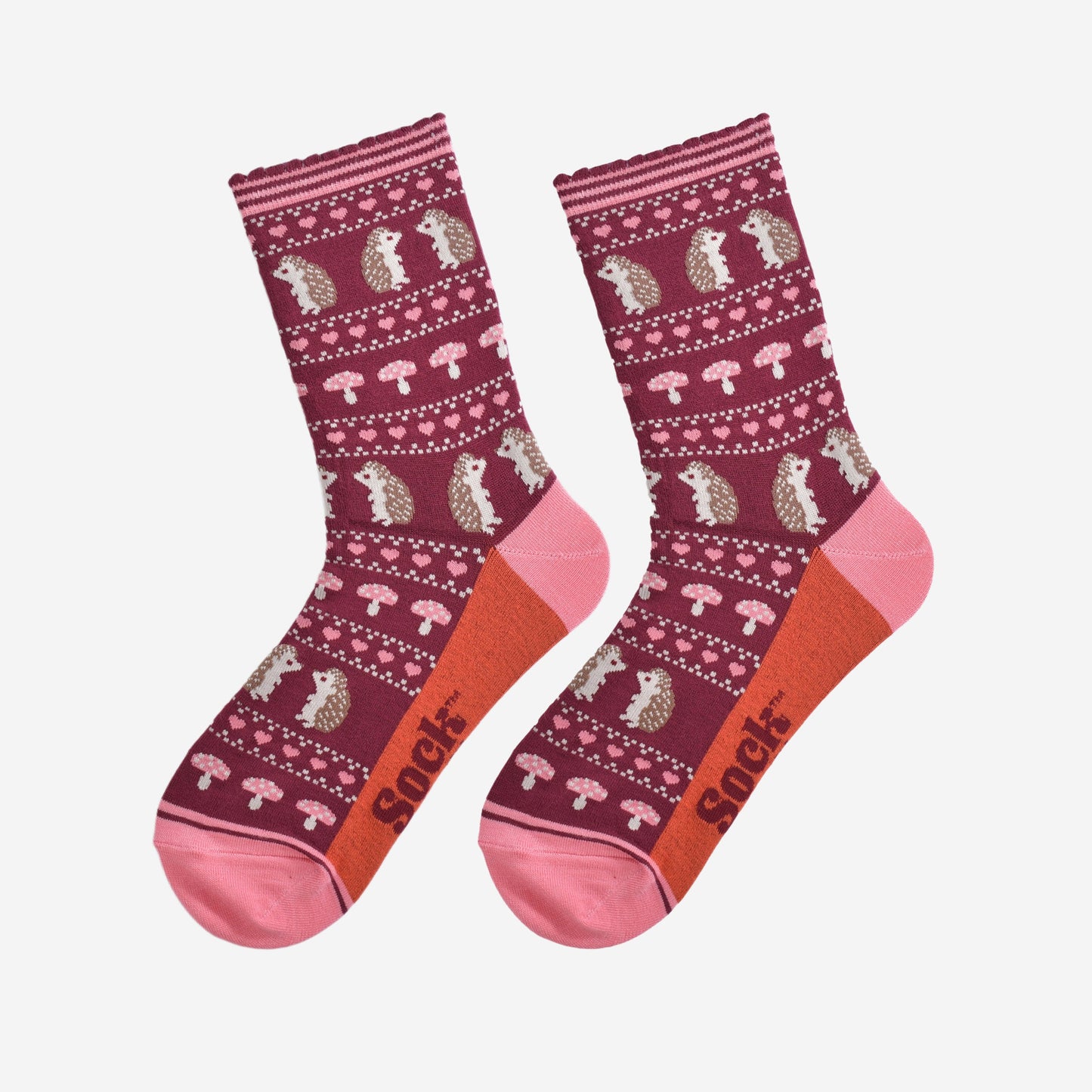 showing the fair isle hedgehog socks laying flat, highlighting the all over pattern featuring hedgehogs, toadstools and pink love hearts