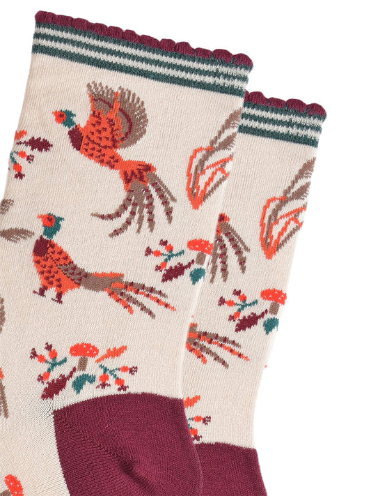 close up of the pheasants, they are illustrated in orange and red and appear to be walking and flying, surrounding the pheasants are autumn leaves and red toadstools