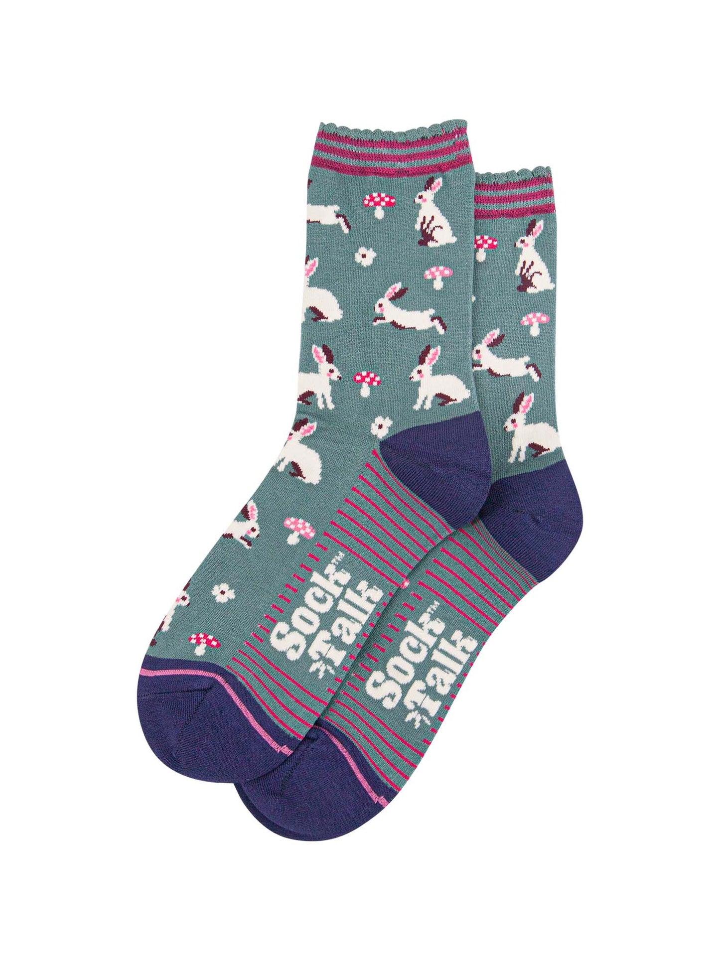 showing the woodland rabbit socks laying flat, there are white rabbits, hopping, sitting and standing among pink toadstools and white flowers, the solve of the socks has pink stripes in contrast to the green base of the design
