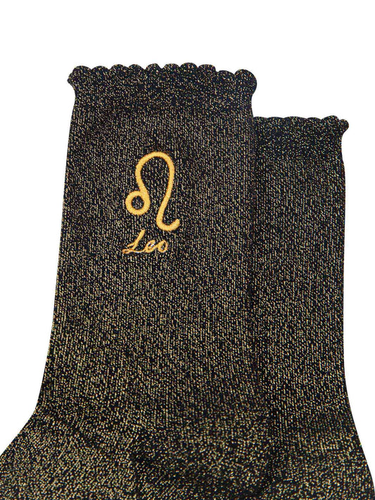 close up of the gold embroidered zodiac detail on the ankle of the socks, showing clearly the symbol of and word leo