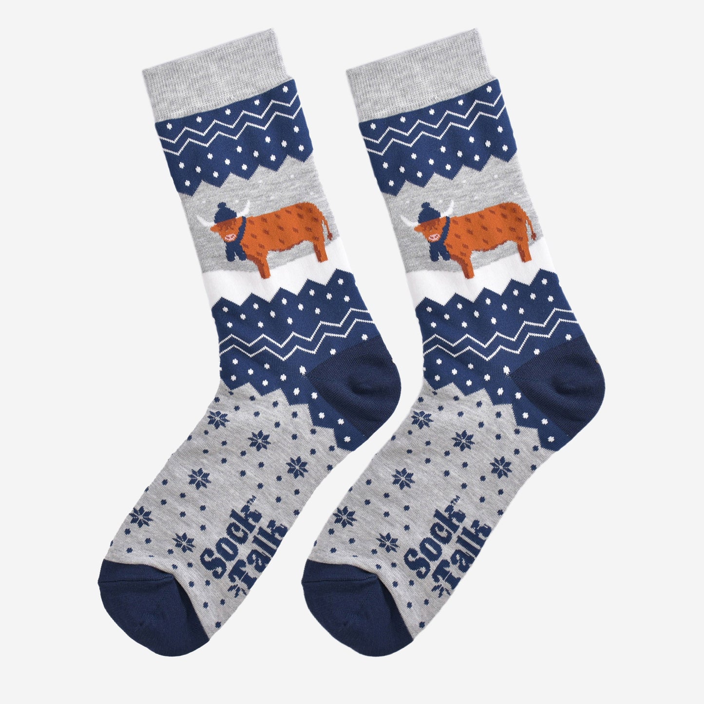 showing these grey and blue fair isle pattern highland cow socks laying flat, showing the overall festive winter pattern