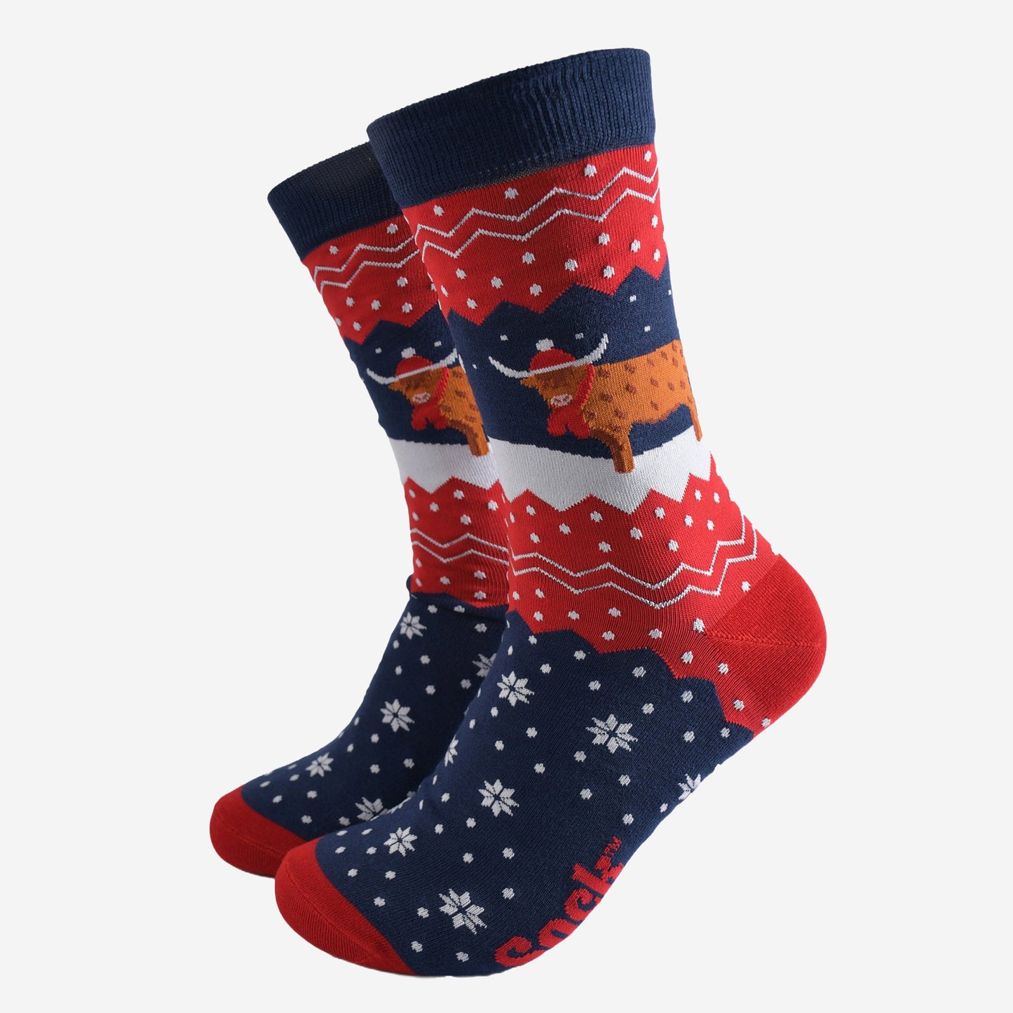 navy blue and red bamboo socks with a fair isle zig zag and snowflake pattern, featuring a highland cow standing in a snowy field wearing a santa hat