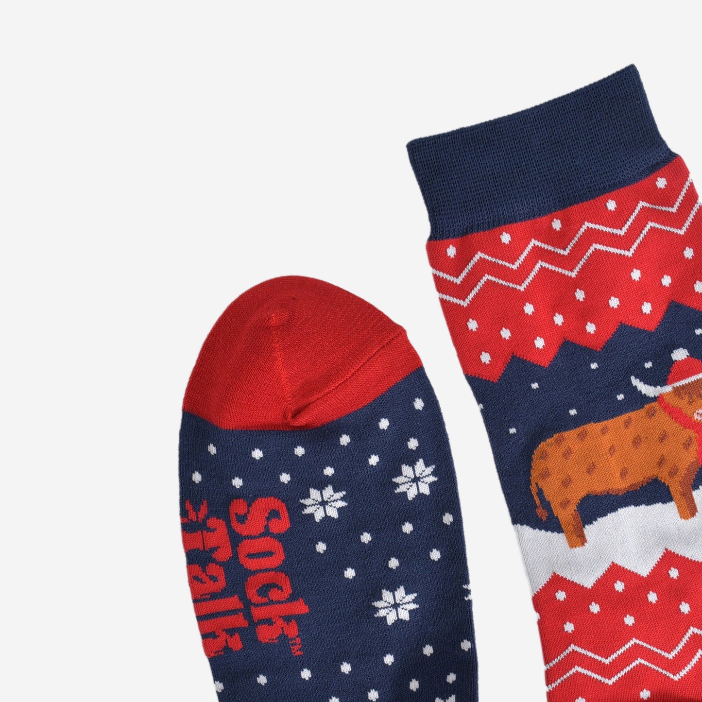 showing the toe and cuff of the socks, showing clearly the fair isle pattern and highland cow, the cow is wearing a winter hat and scarf