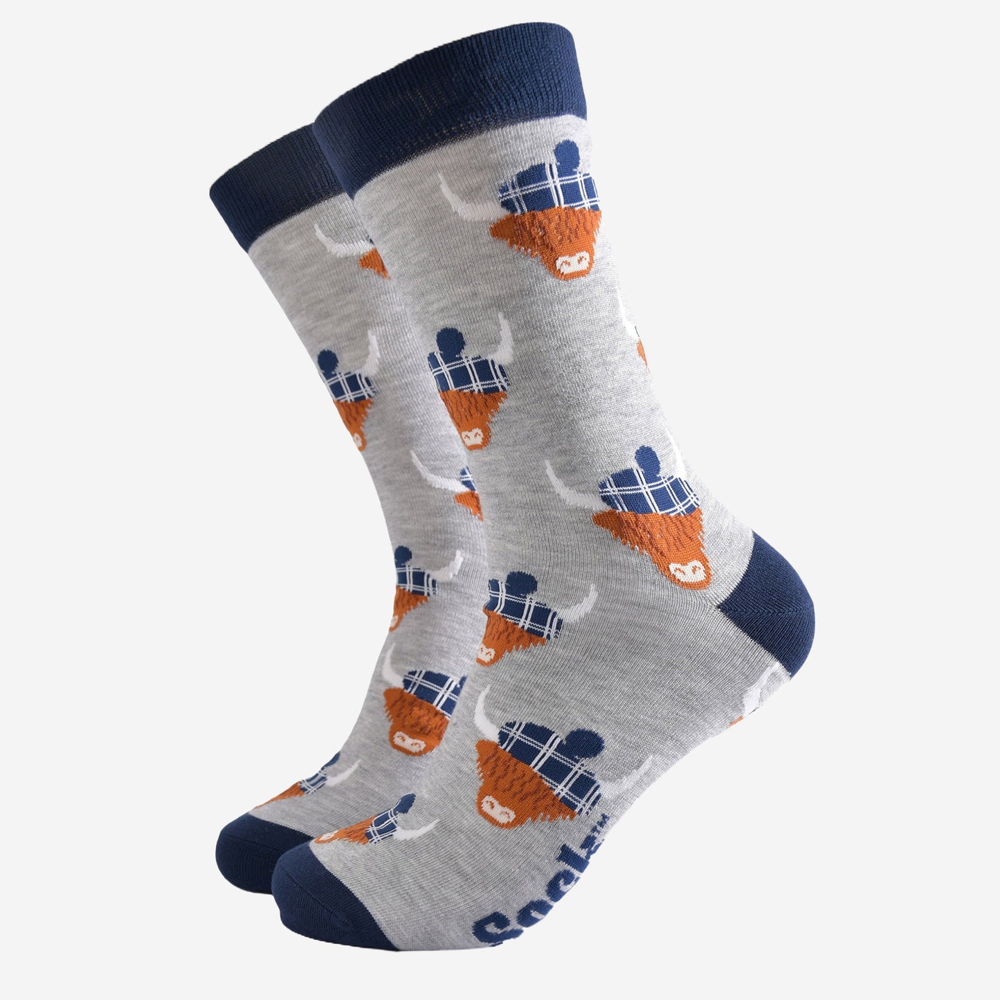 light grey socks with a navy blue heel, toe and cuff with an all over pattern of highland cows wearing tartan pom pom hats