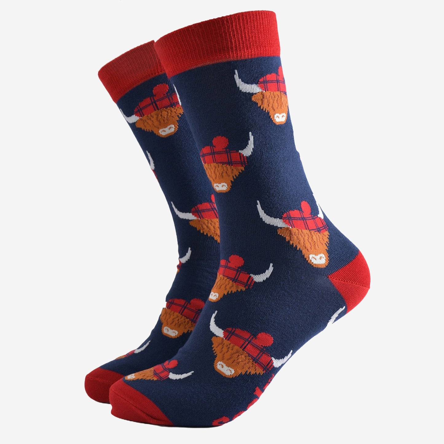 navy blue socks with red heel, toe and cuff with an all over pattern of highland cows wearing tartan pom pom hats