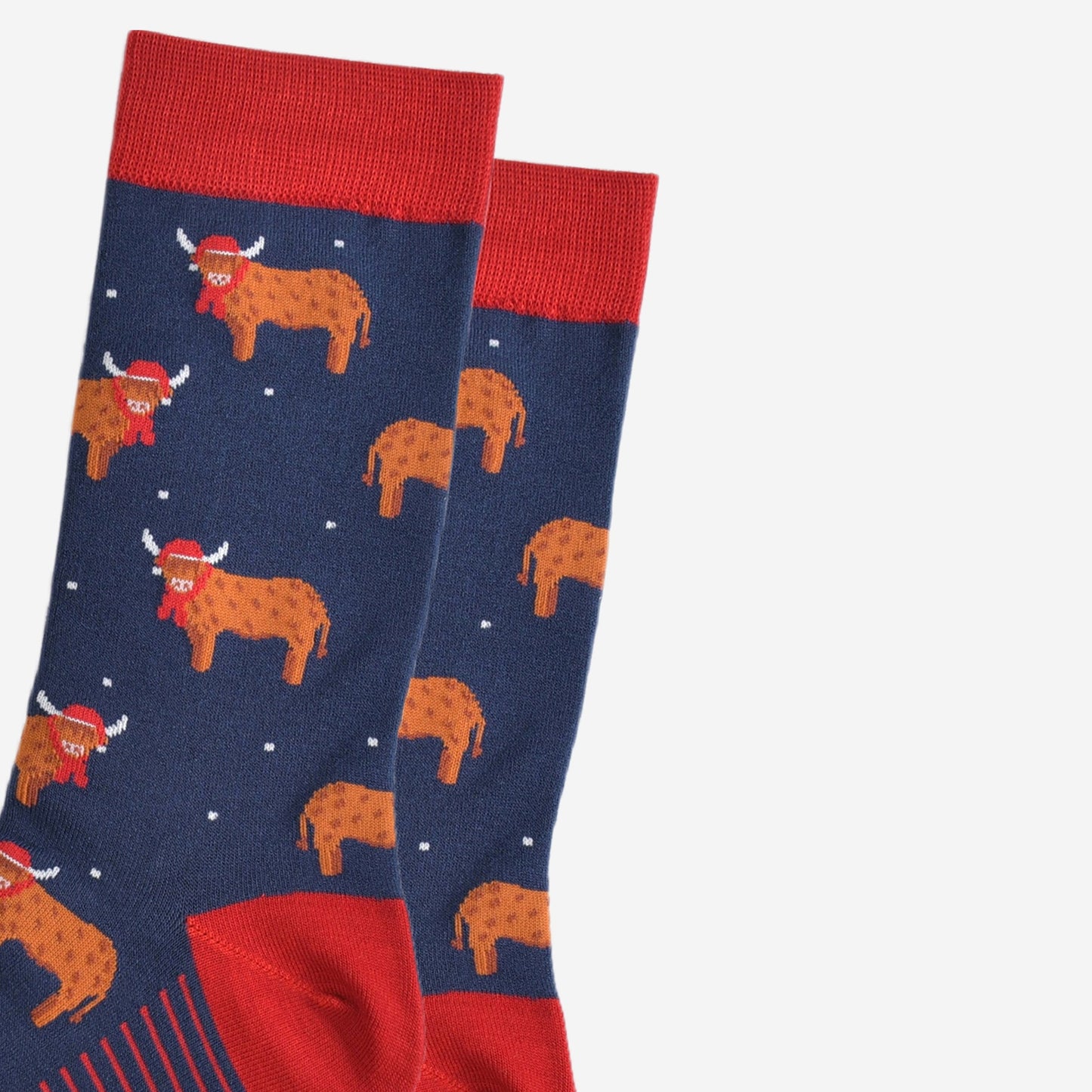 close up of the orange highland cows on the socks, the cows are standing up and they are designed to look like they have long hair, they are also wearing a red santa hat and scarf