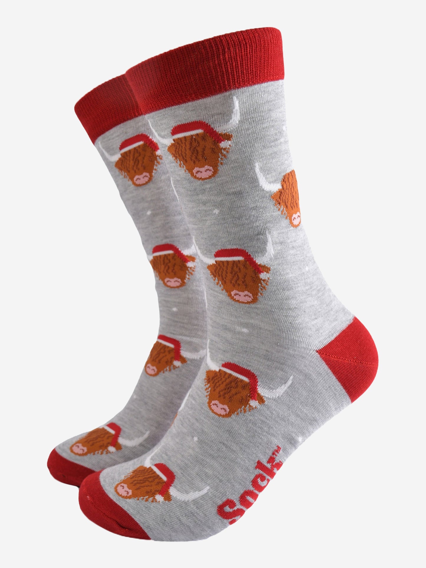 light grey socks with a red heel, toe and cuff with an all over pattern of highland cows wearing santa hats