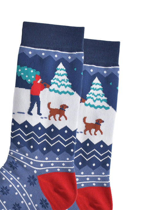 close up of the man and his dog design on the ankle, the man is carrying a christmas tree while walking through the snow with a brown dog