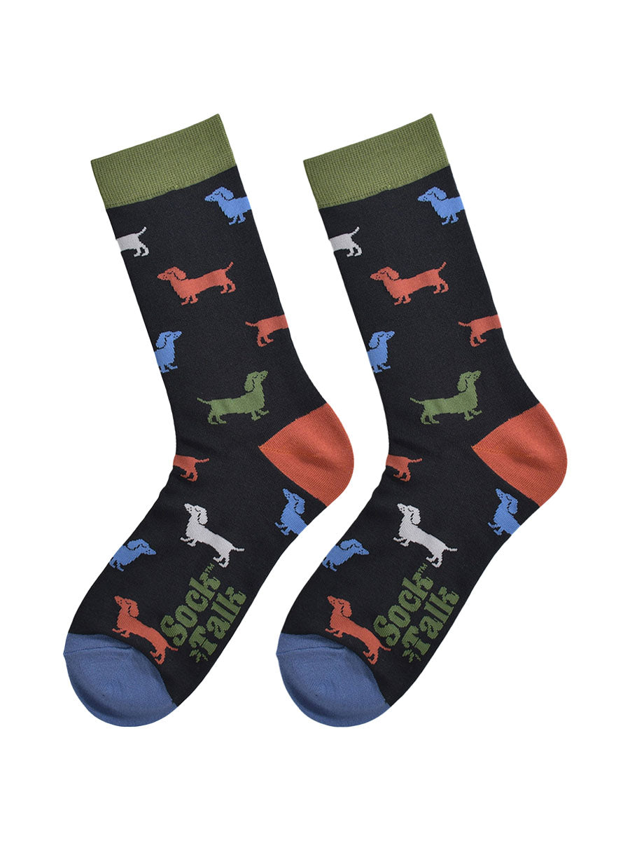 colourful sausage dog socks laying flat, showing the all over pattern of green, orange, blue and grey sausage dogs on a black sock