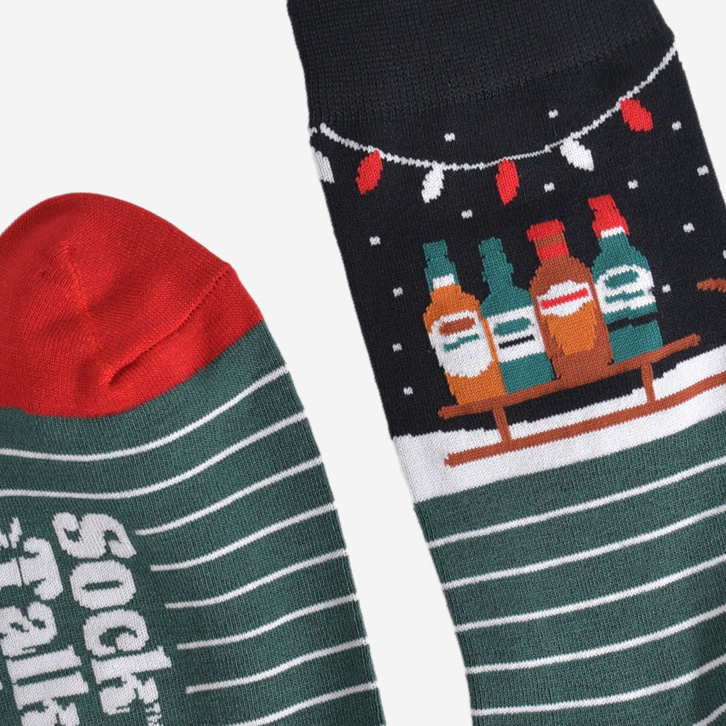 close up of the cuff and the toe of the socks, the toe is red in contrast to green of the socks, cuff is black in keeping with the winter night scene featuring the sledge and party lights
