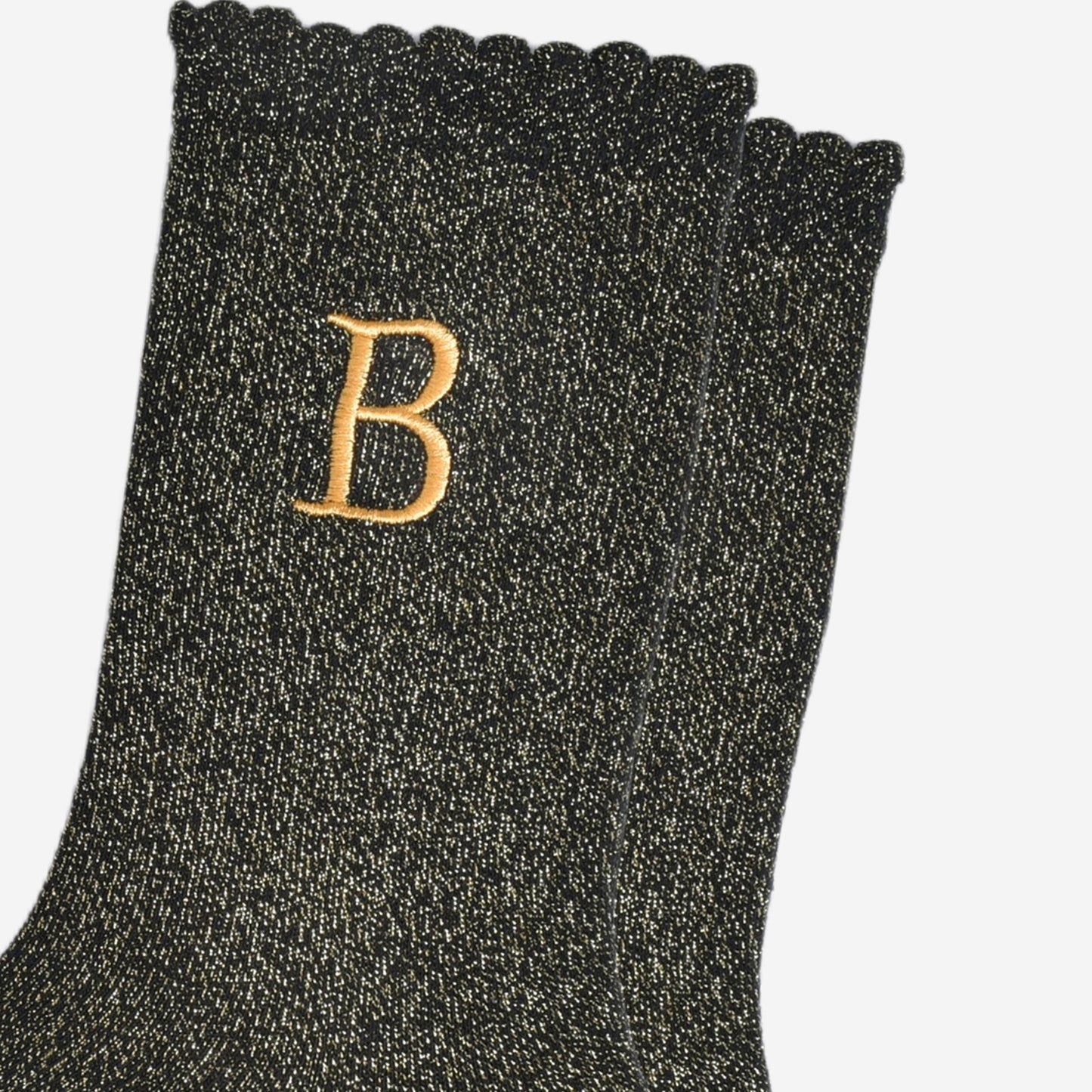 close up of the gold embroidered capital letter b on the ankle of the socks