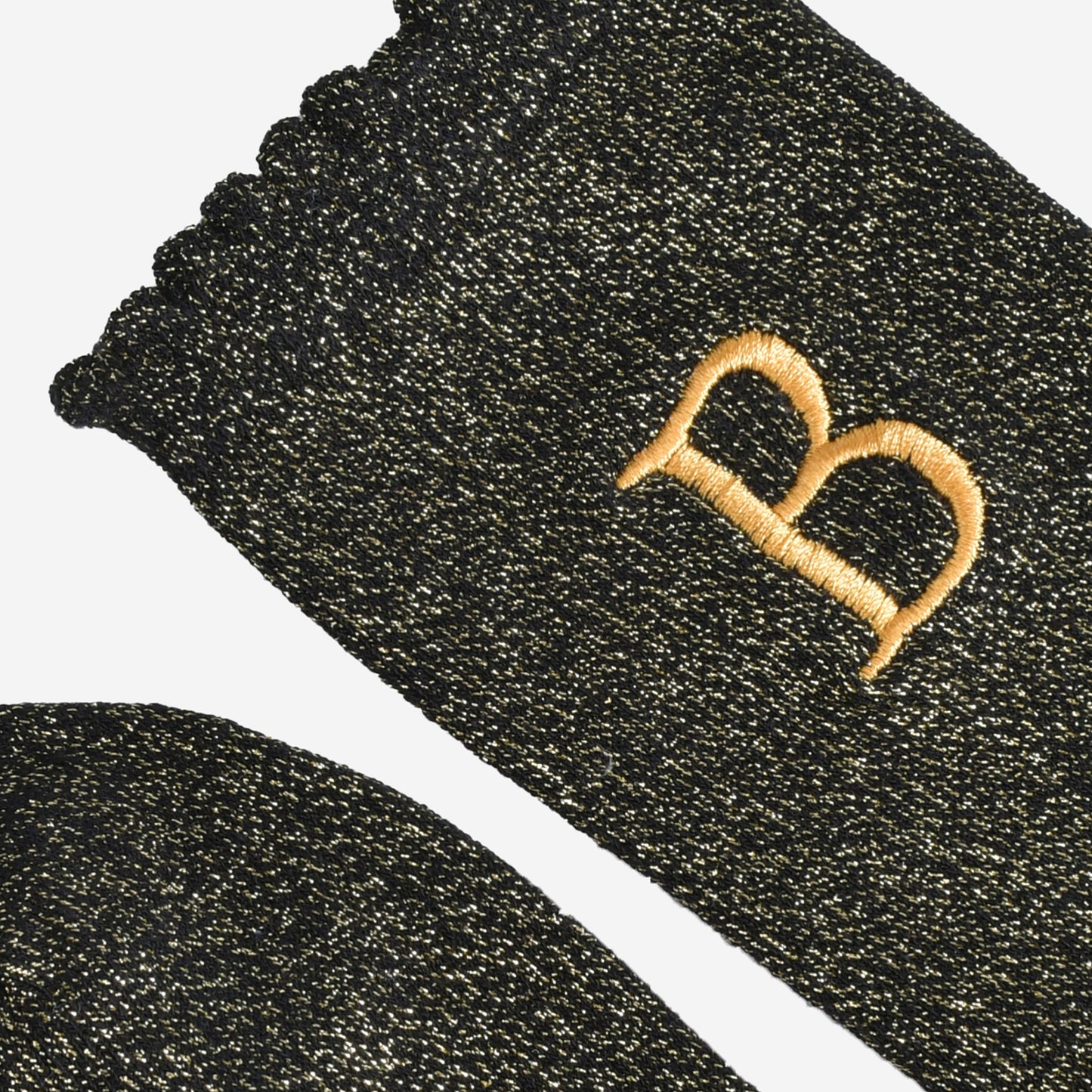 close up of the scalloped cuff on the socks, the toe is the same black and gold as the rest of the socks