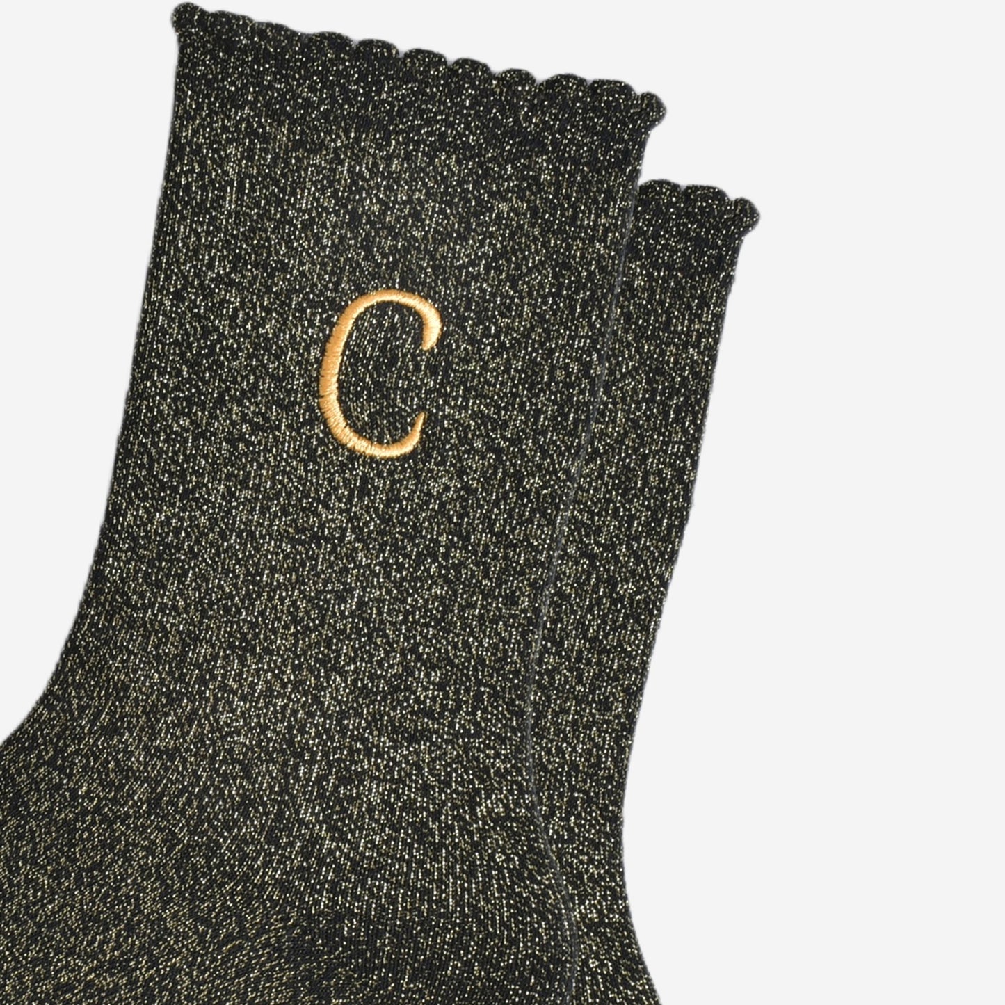close up of the gold embroidered capital letter c on the ankle of the socks