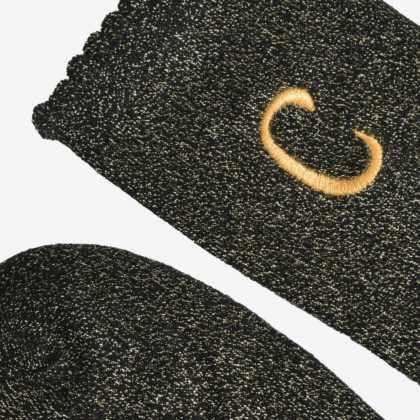 close up of the scalloped cuff on the socks, the toe is the same black and gold as the rest of the socks