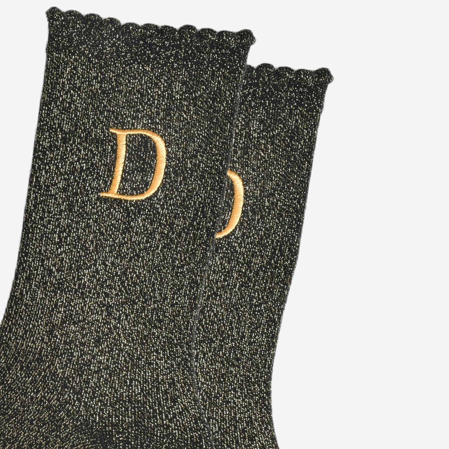 close up of the gold embroidered capital letter d on the ankle of the socks